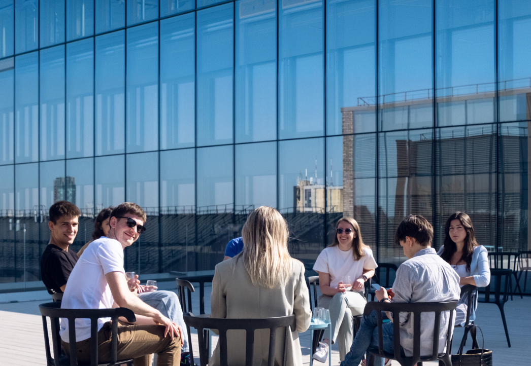 Nord Security colleagues talking at tables on a sunlit rooftop terrace.
