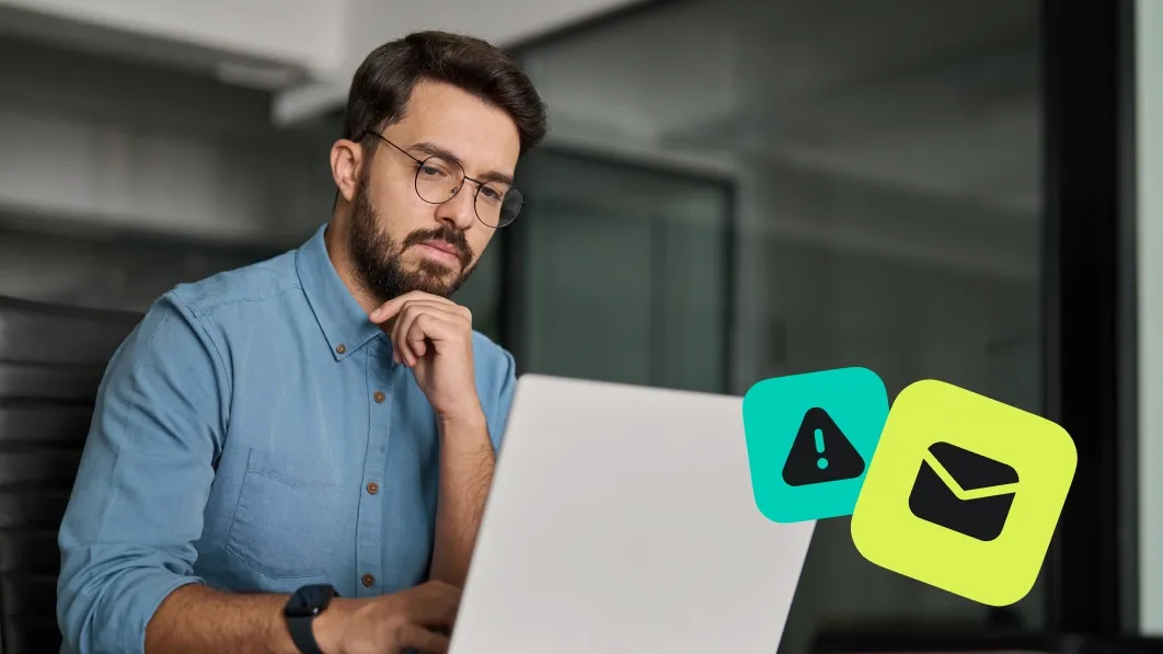 A man at computer with email alert icons showing signs of a phishing scam attempt