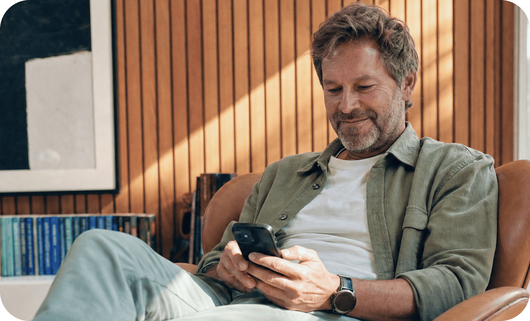 A participant relaxing in an armchair and smiling at his phone