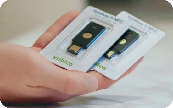 Hand holding two packaged YubiKey 5 NFC security keys