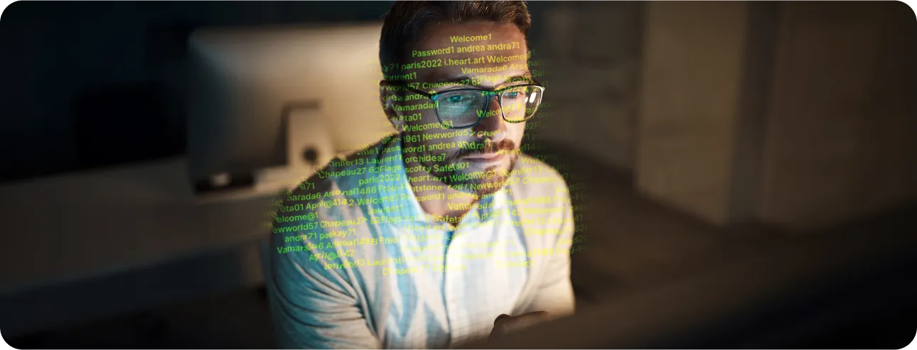 Man with glasses looks at computer with code reflected on his face.