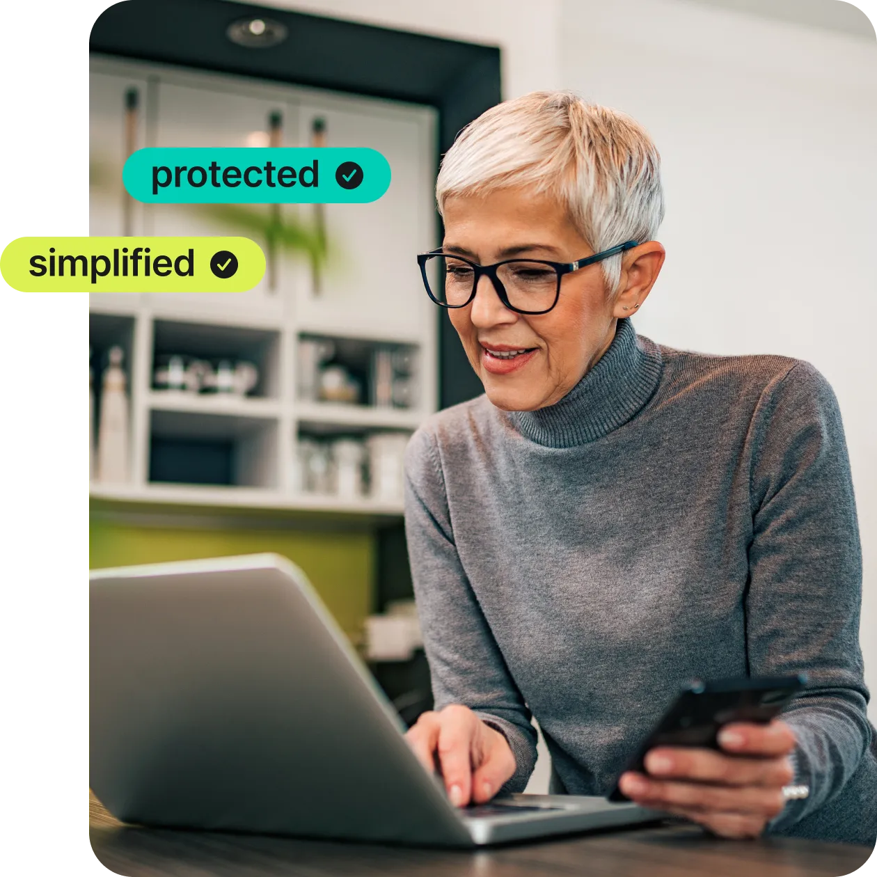 woman with short grey hair and grey turtleneck with a laptop using NordPass in the kitchen