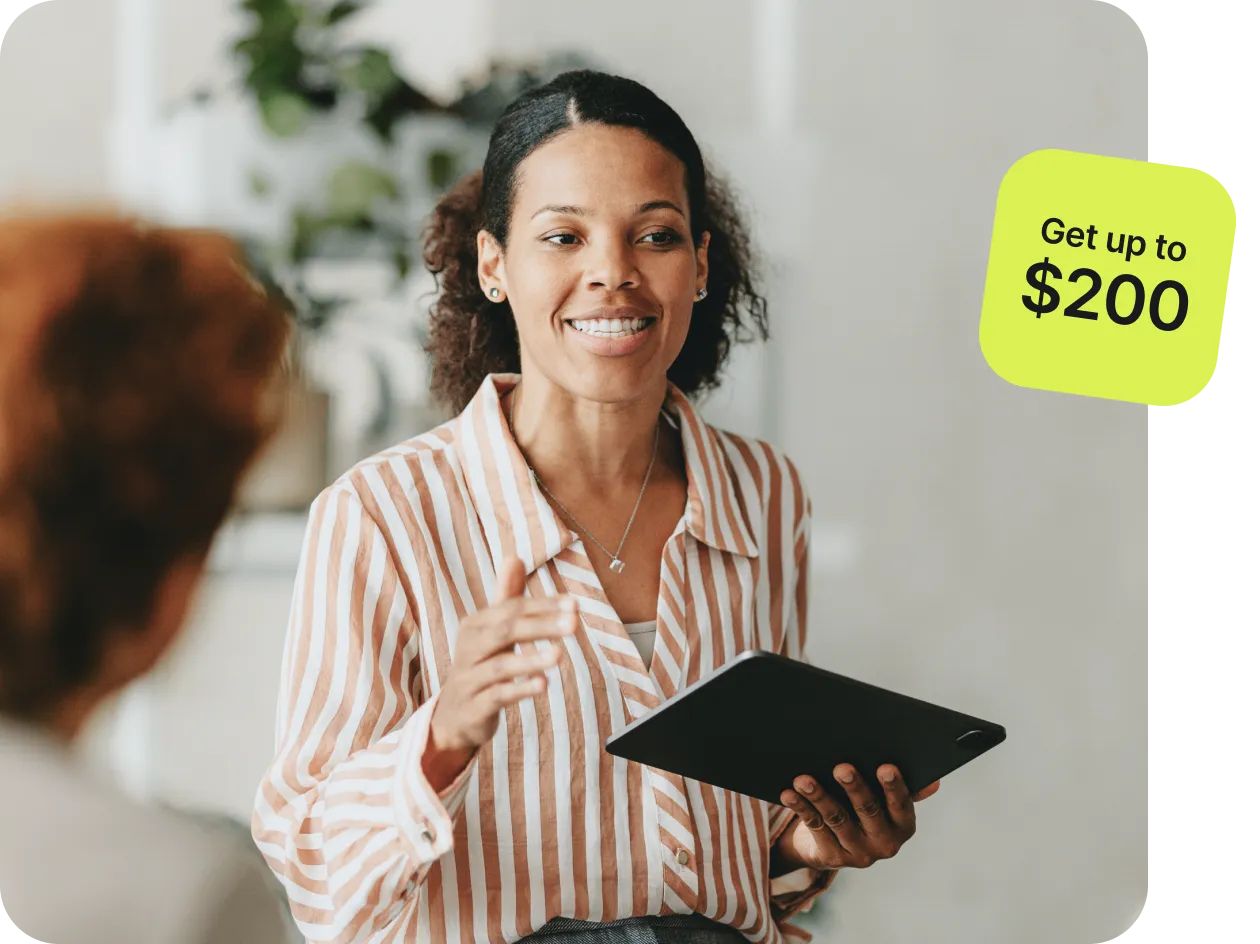 A smiling person holding a tablet and gesturing while speaking, with a caption on a bright green background that reads "Get up to $200."